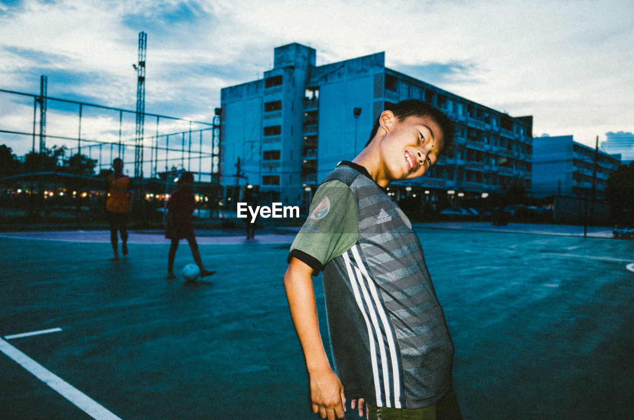 YOUNG MAN STANDING IN FRONT OF SKYSCRAPER