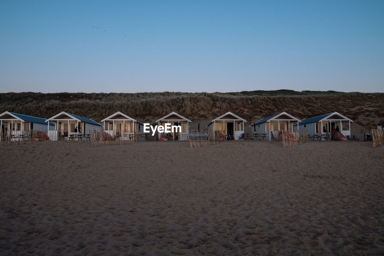BEACH HUTS BY BUILDINGS AGAINST CLEAR SKY