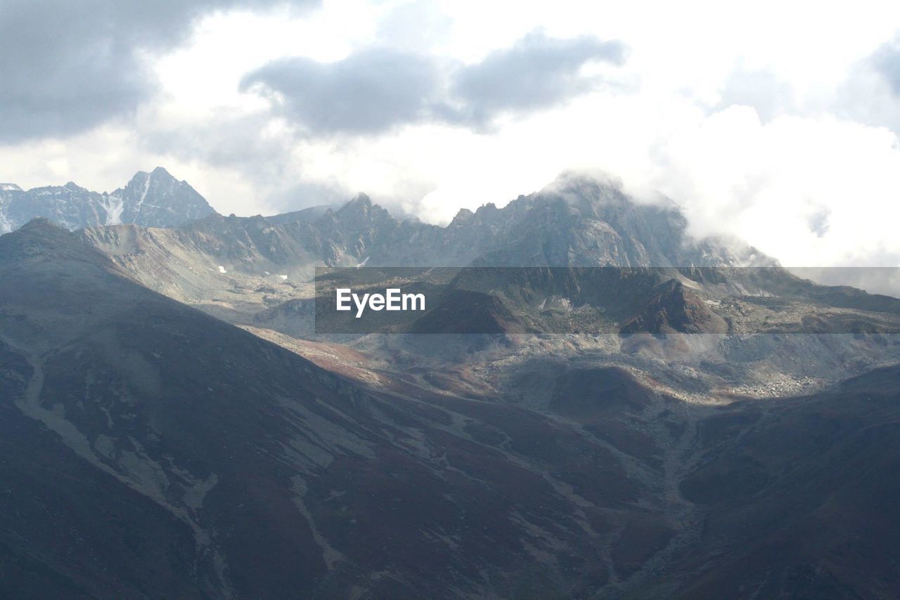 SCENIC VIEW OF MOUNTAINS AGAINST CLOUDY SKY