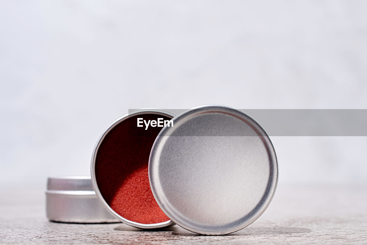 Colorful lip balms in round tin cases on light background with shadow overlay, mockup design, label