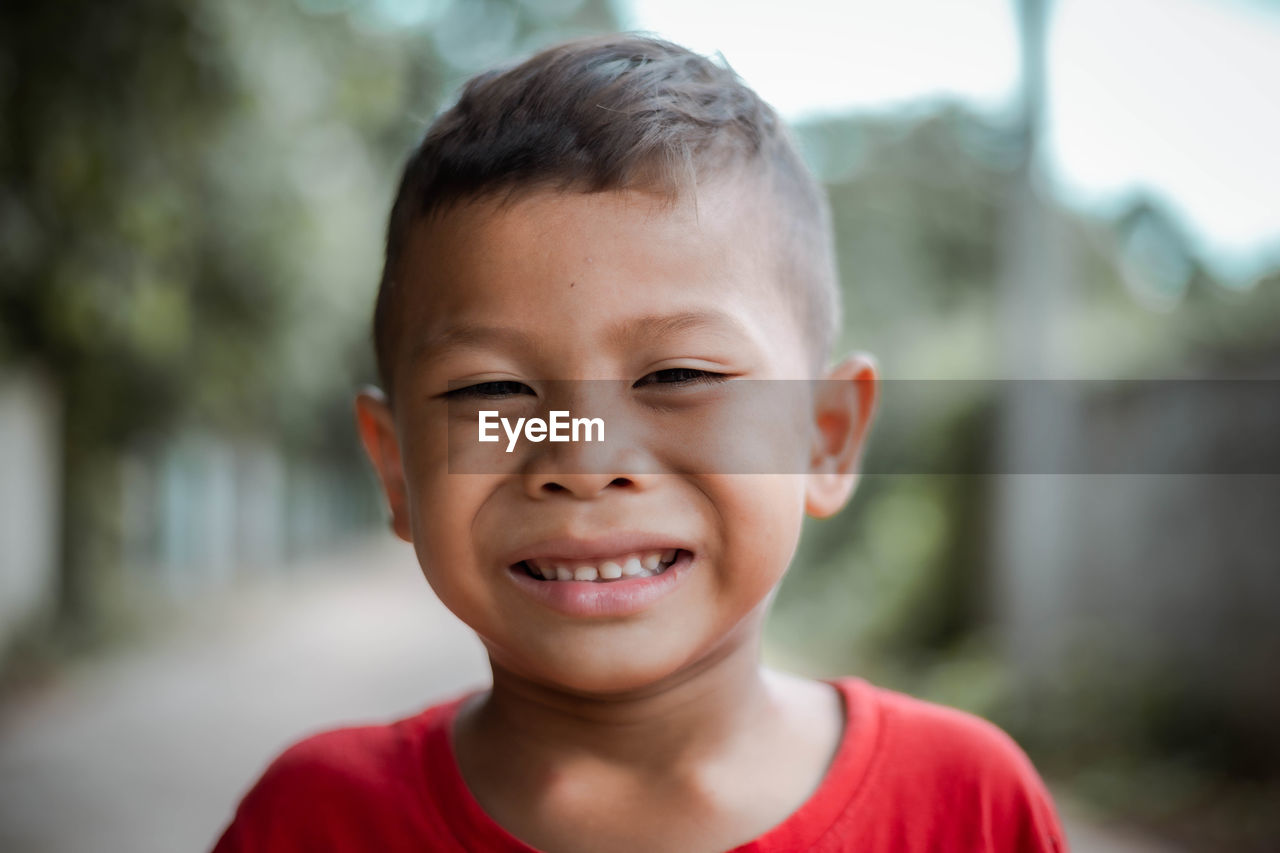 Close-up portrait of smiling boy standing outdoors