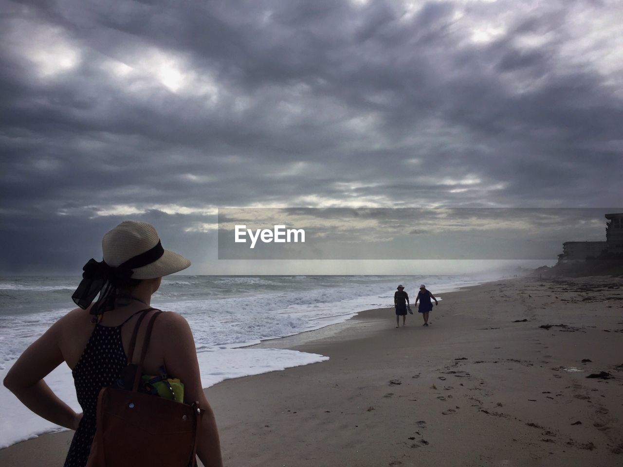 People at beach against cloudy sky