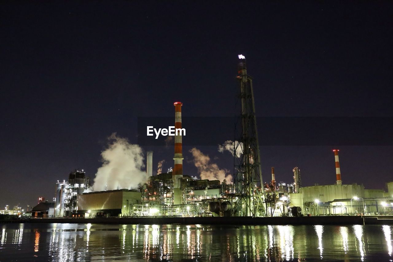 VIEW OF ILLUMINATED FACTORY AGAINST SKY AT NIGHT