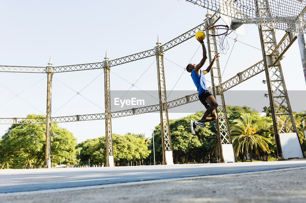 Male basketball player scoring basket at sports court