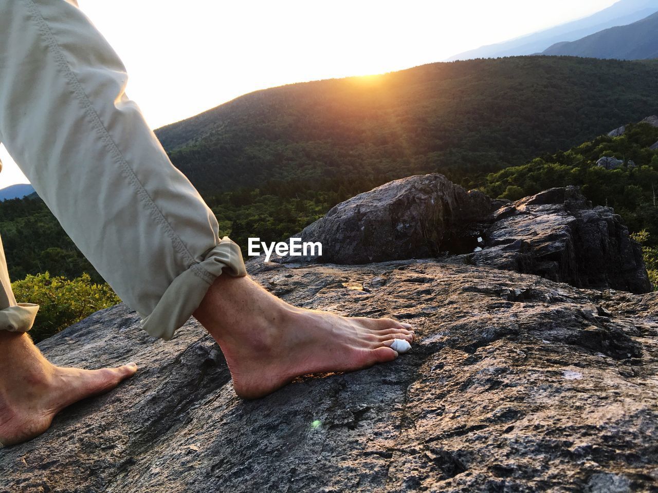 LOW SECTION OF MAN LEGS ON ROCK AGAINST SKY