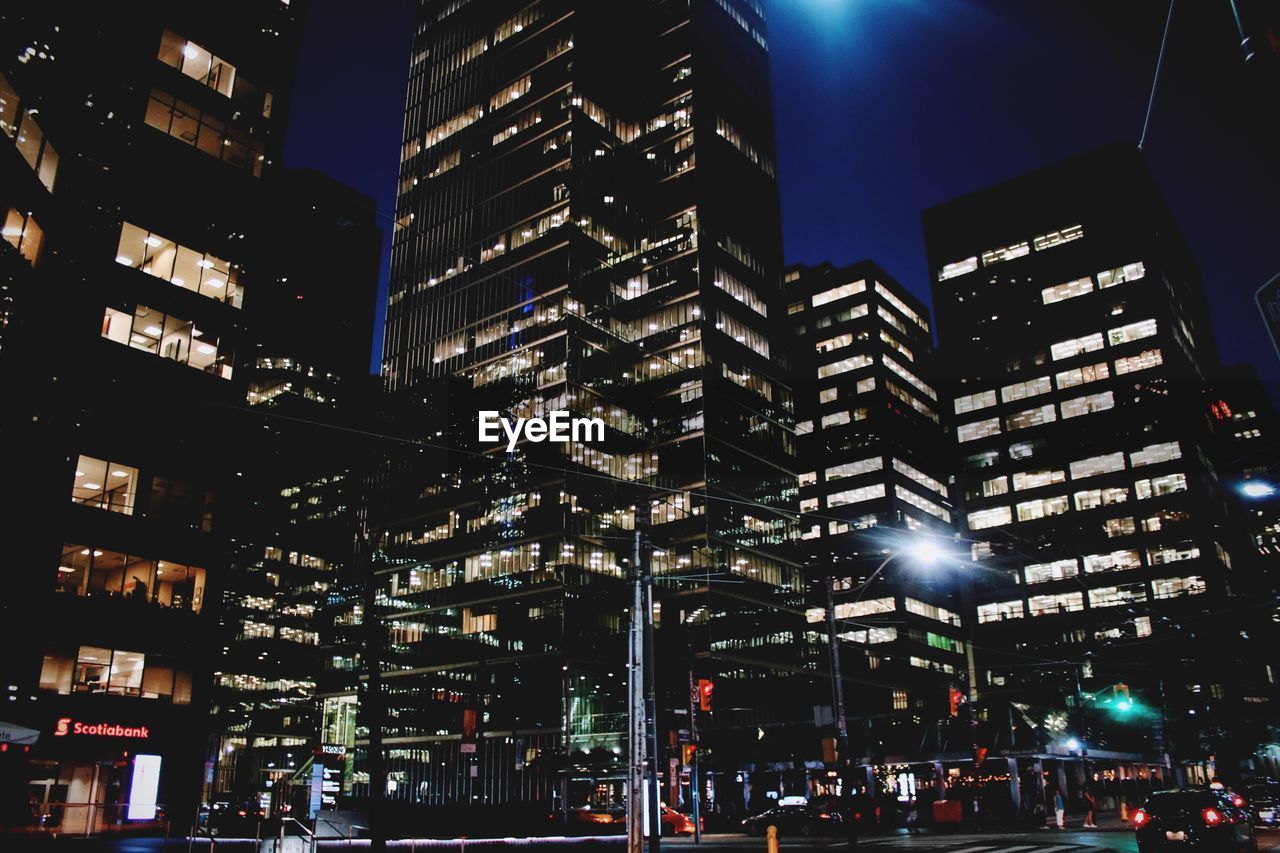 Low angle view of illuminated city against sky at night