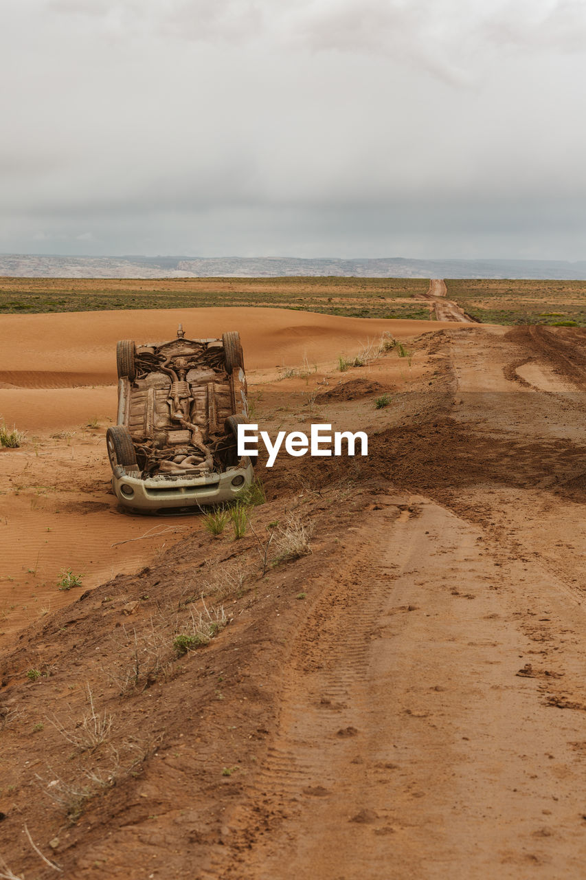 Upside down car that has flipped on a muddy dirt road in utah desert