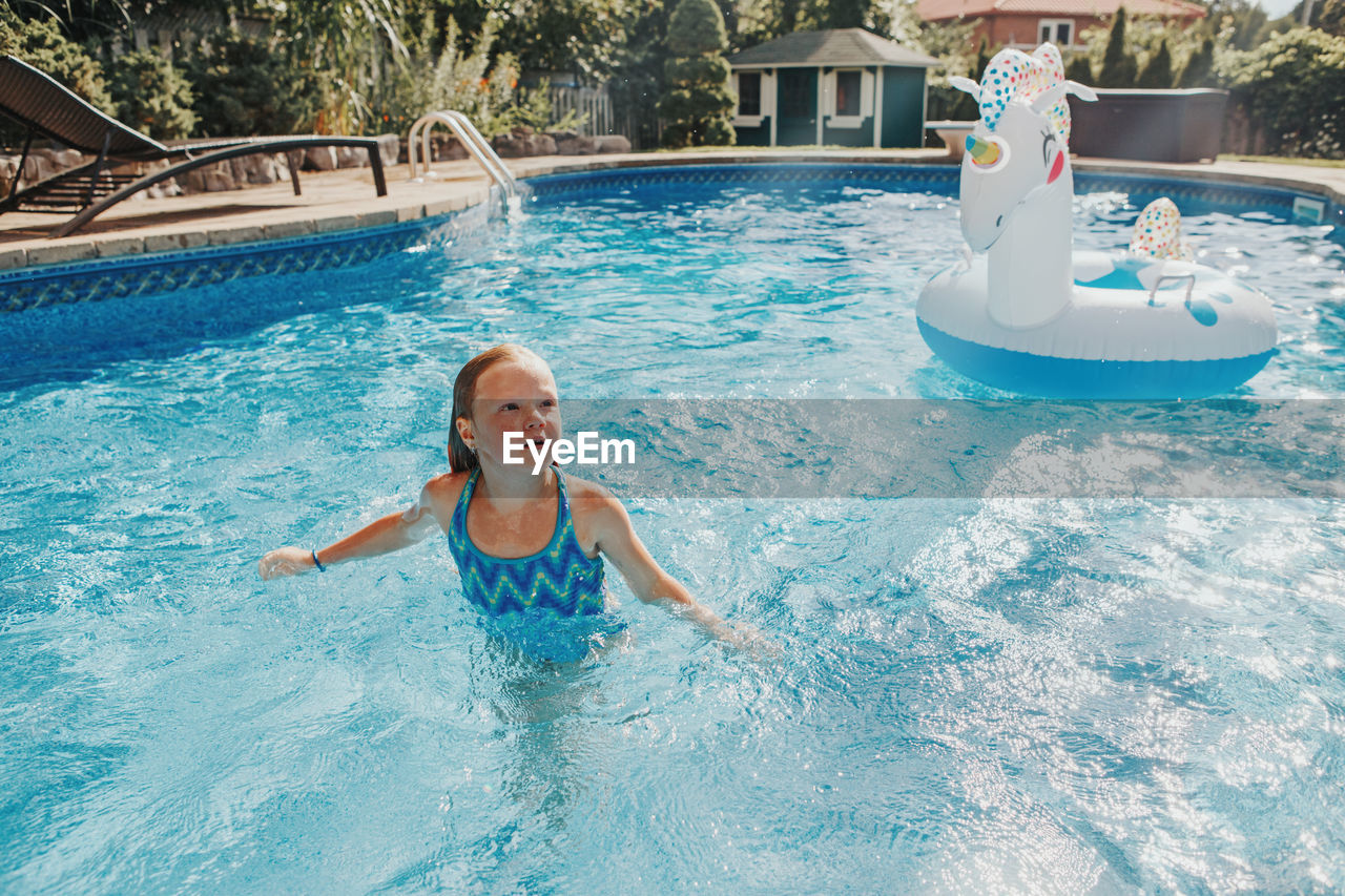 Cute girl standing in swimming pool