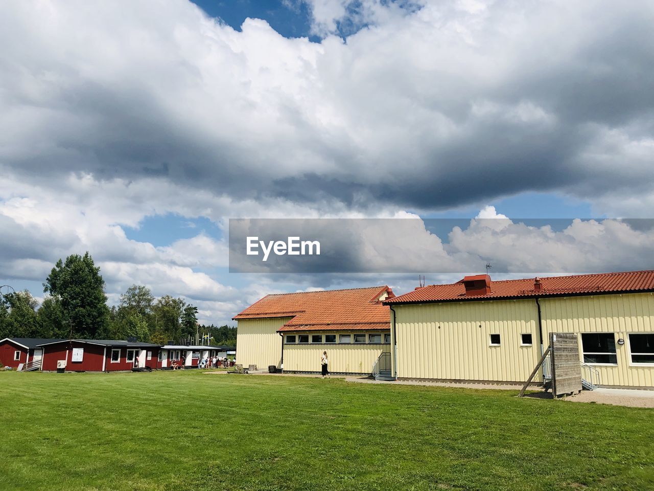 HOUSES BY FIELD AGAINST SKY