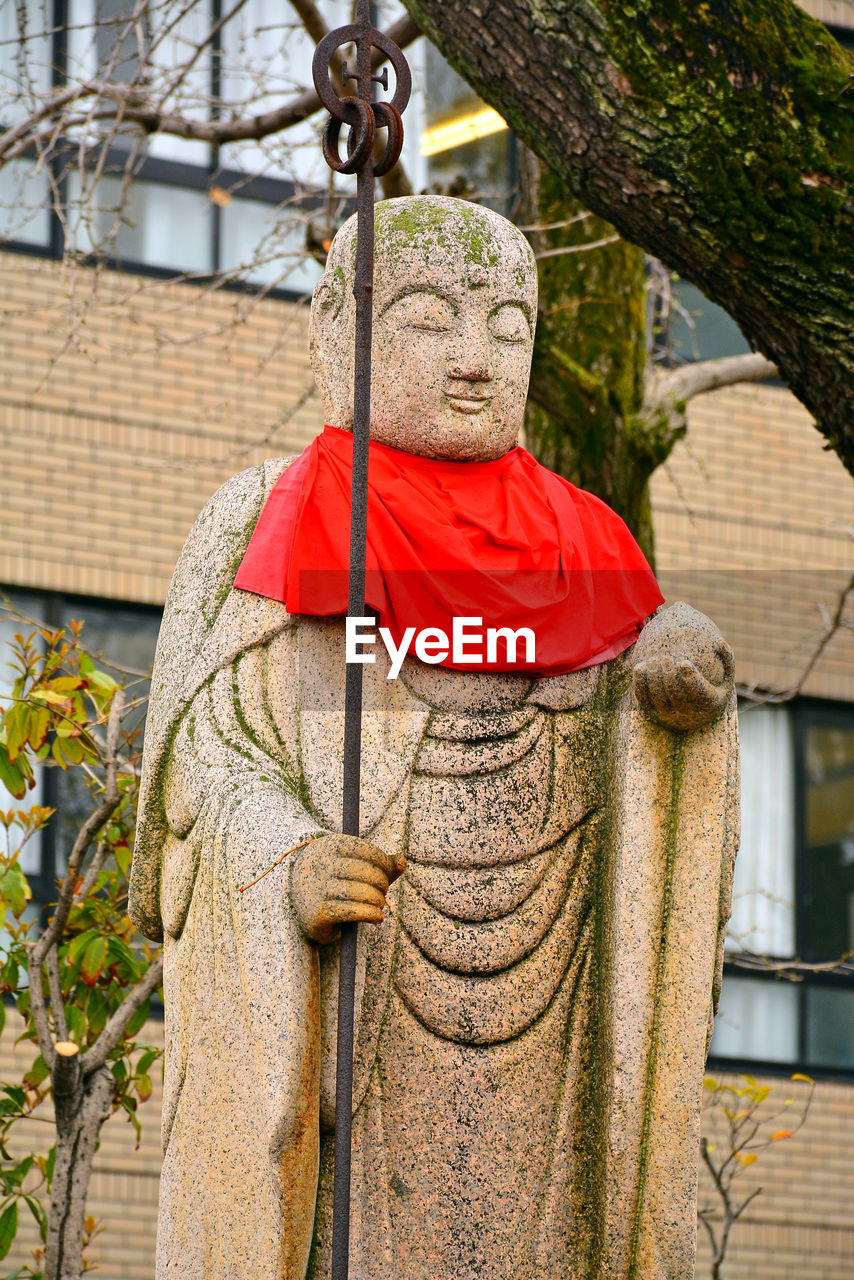 STATUE OF BUDDHA AGAINST TREE