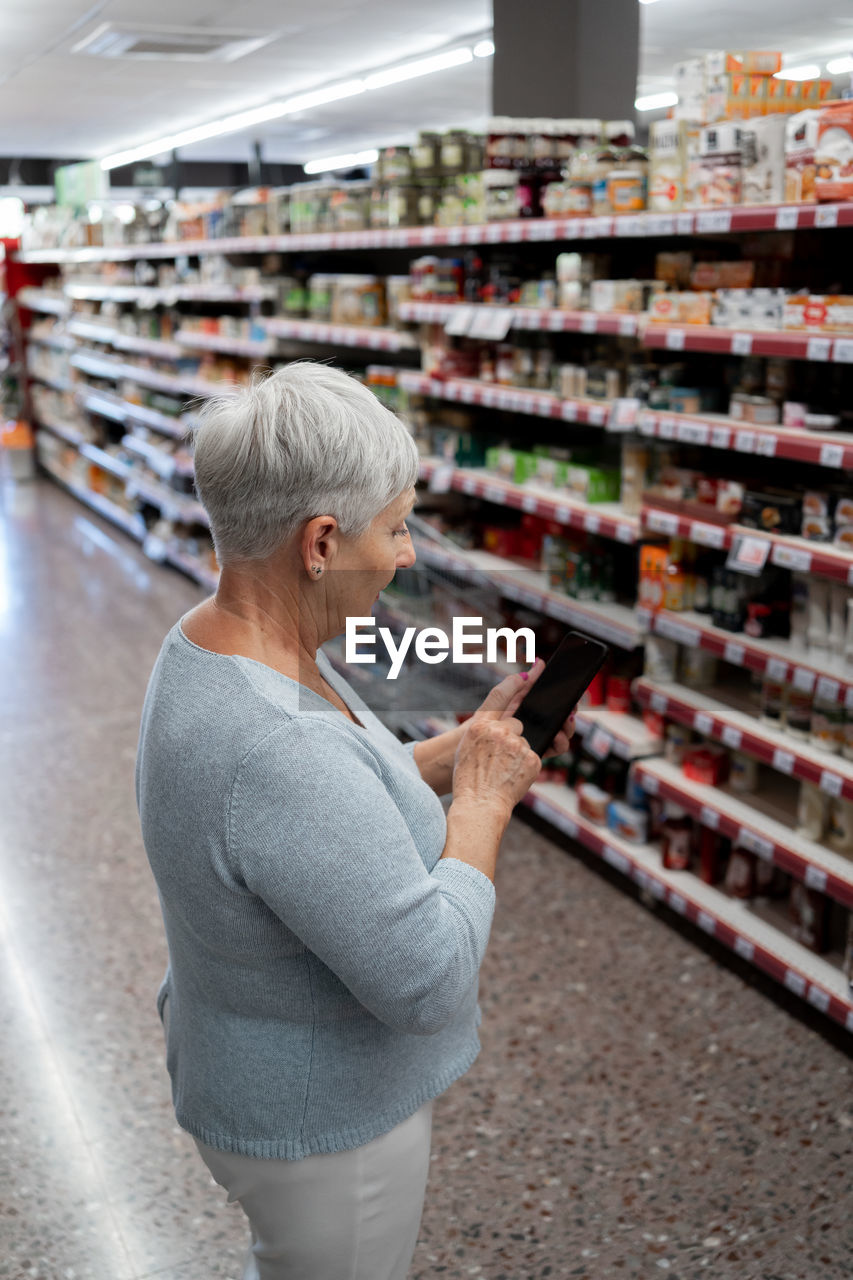 Caucasian elderly woman with white hair shopping in supermarket