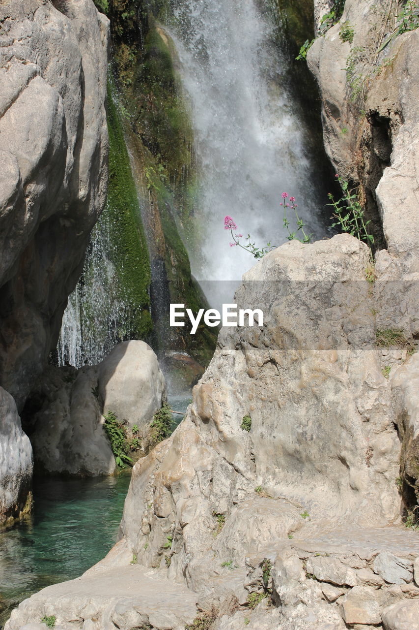 SCENIC VIEW OF WATERFALL AGAINST ROCKS