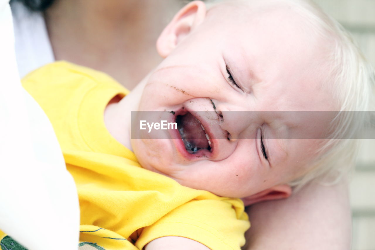Close-up midsection of woman holding crying son