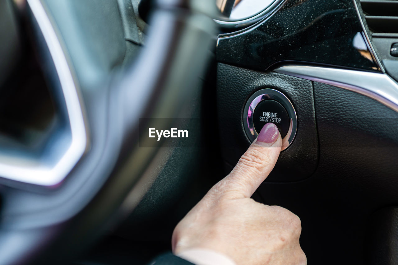 Woman starts the car engine with start-stop button. modern car interior, closeup