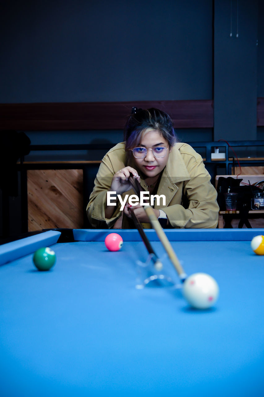 portrait of young woman playing pool