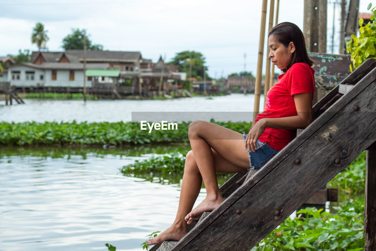 Side view of thoughtful woman sitting on steps by lake