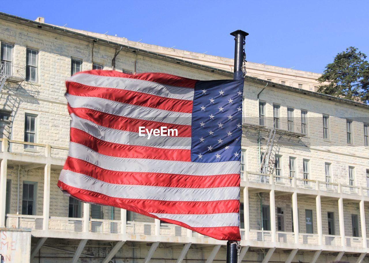 Close-up of american flag against building on sunny day