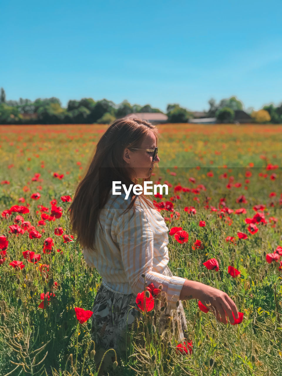 Young woman standing by flowering plants on field