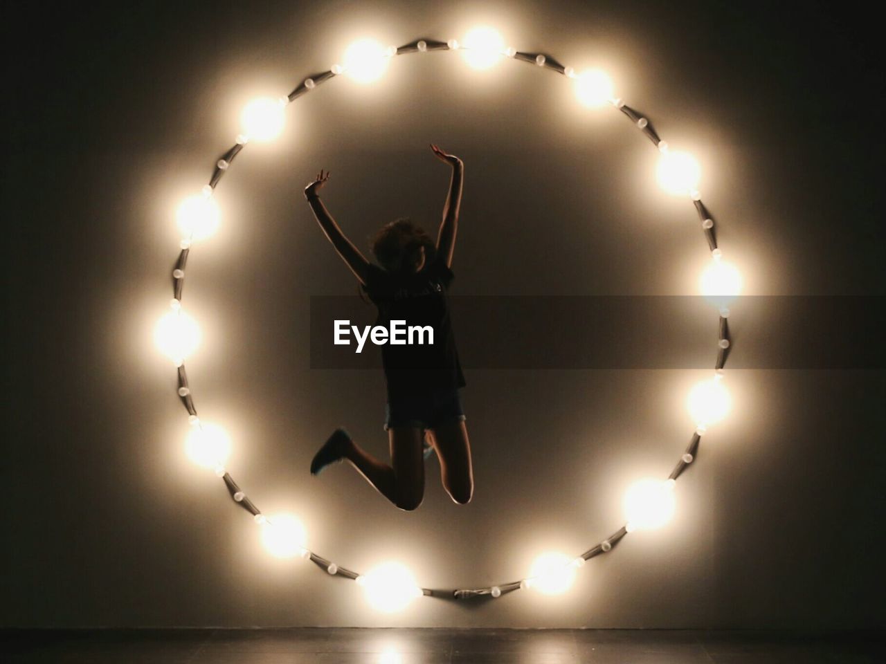 SILHOUETTE WOMAN JUMPING AGAINST BLACK BACKGROUND