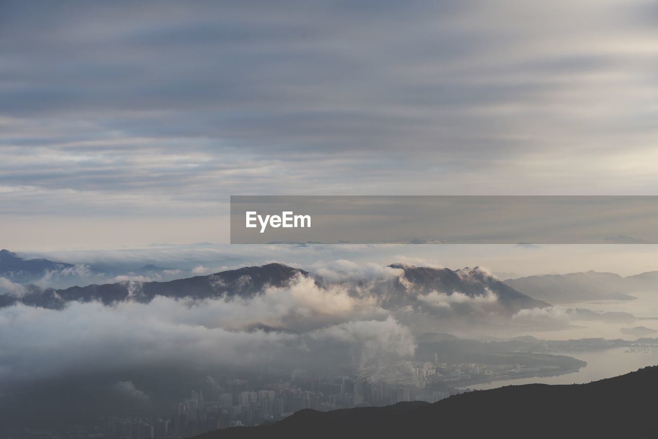 High angle view of cloudy sky over mountains and city