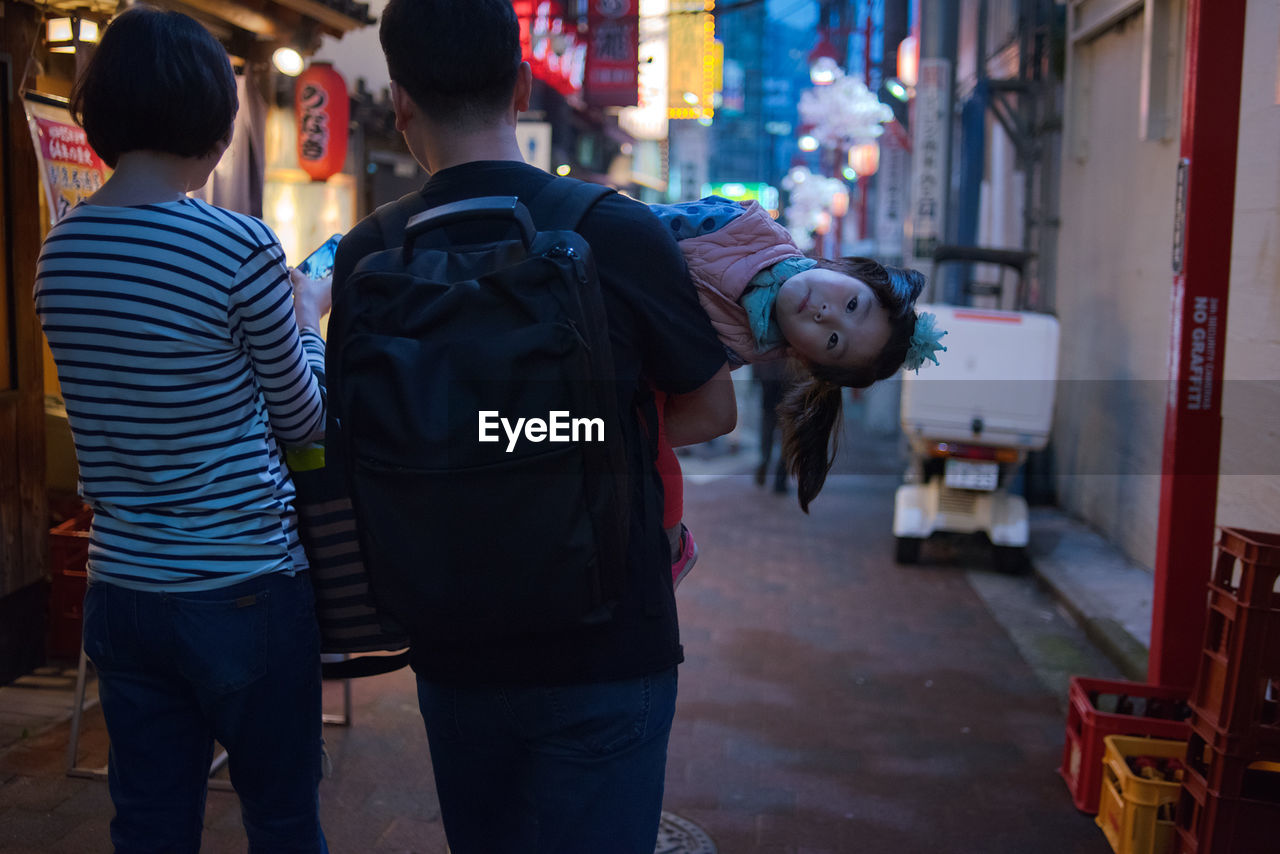 REAR VIEW OF FRIENDS STANDING ON STREET