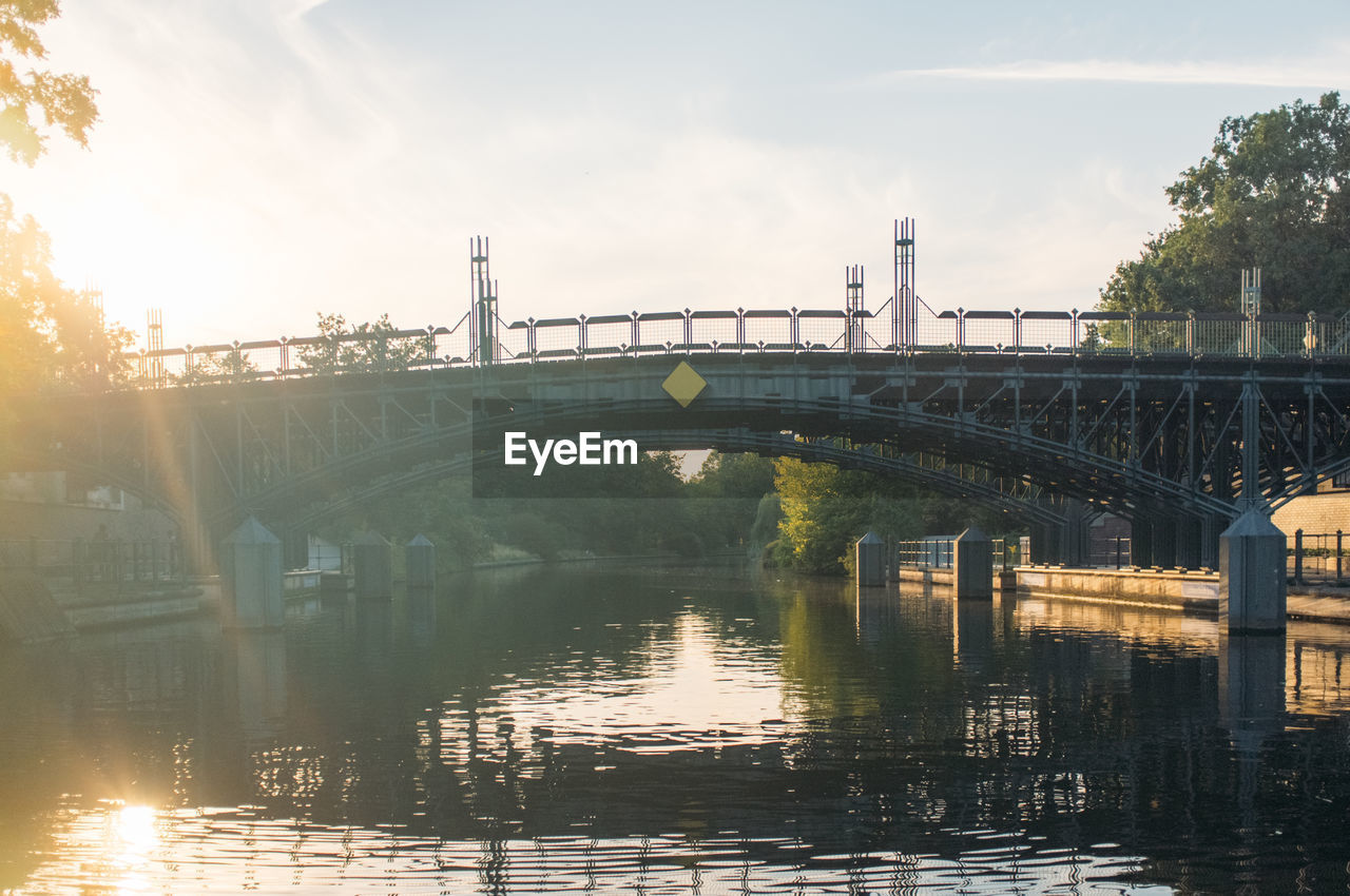 Arch bridge over river against sky on sunny day