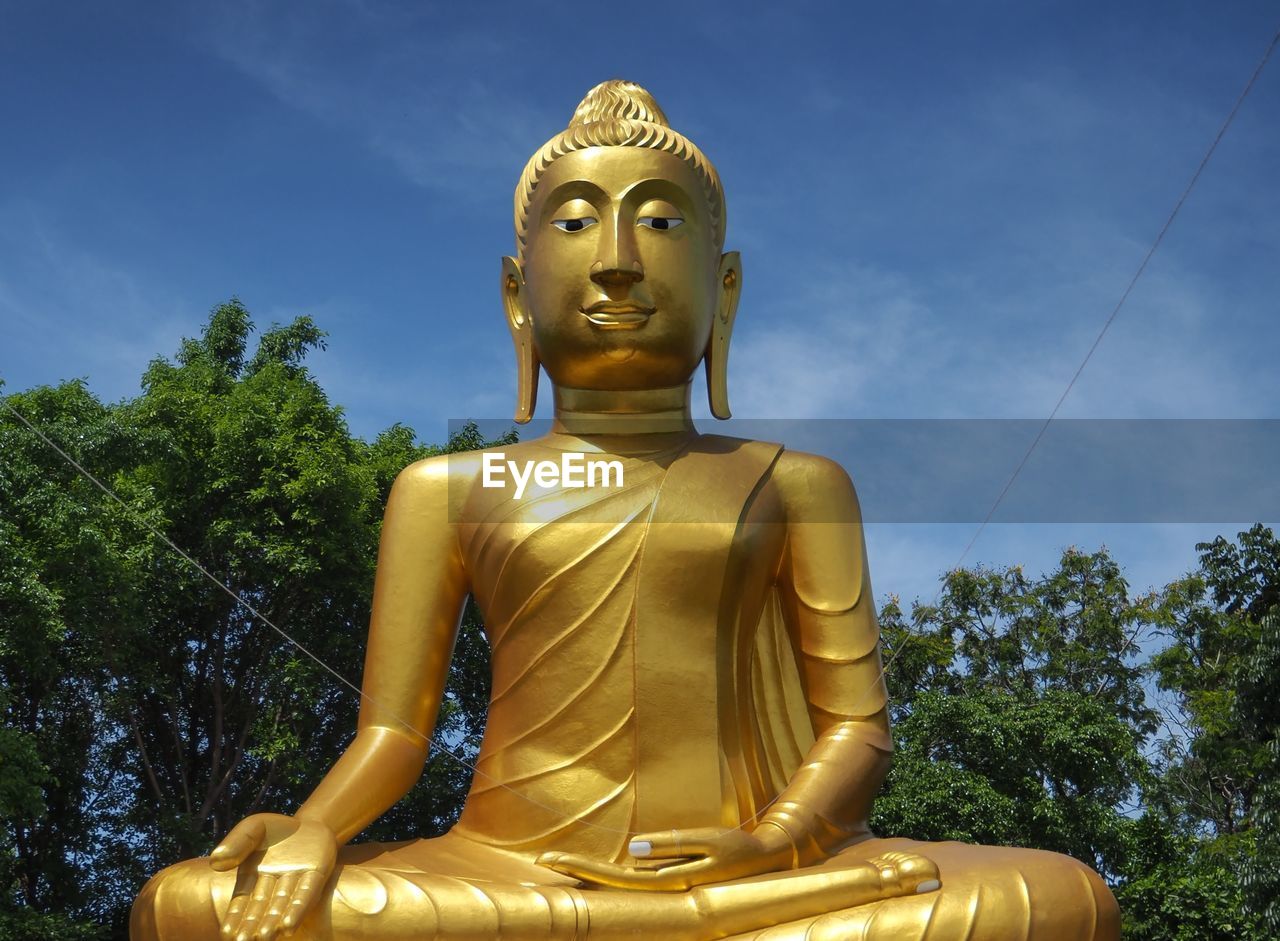 Low angle view of buddha statue against sky