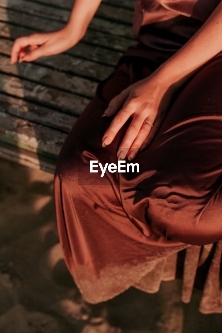 Low section of woman sitting on bench outdoors