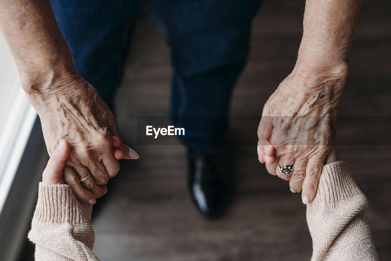 Senior woman holding granddaughter's hands at home