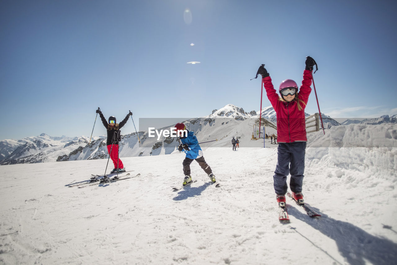 Full length of family enjoying while skiing against clear sky