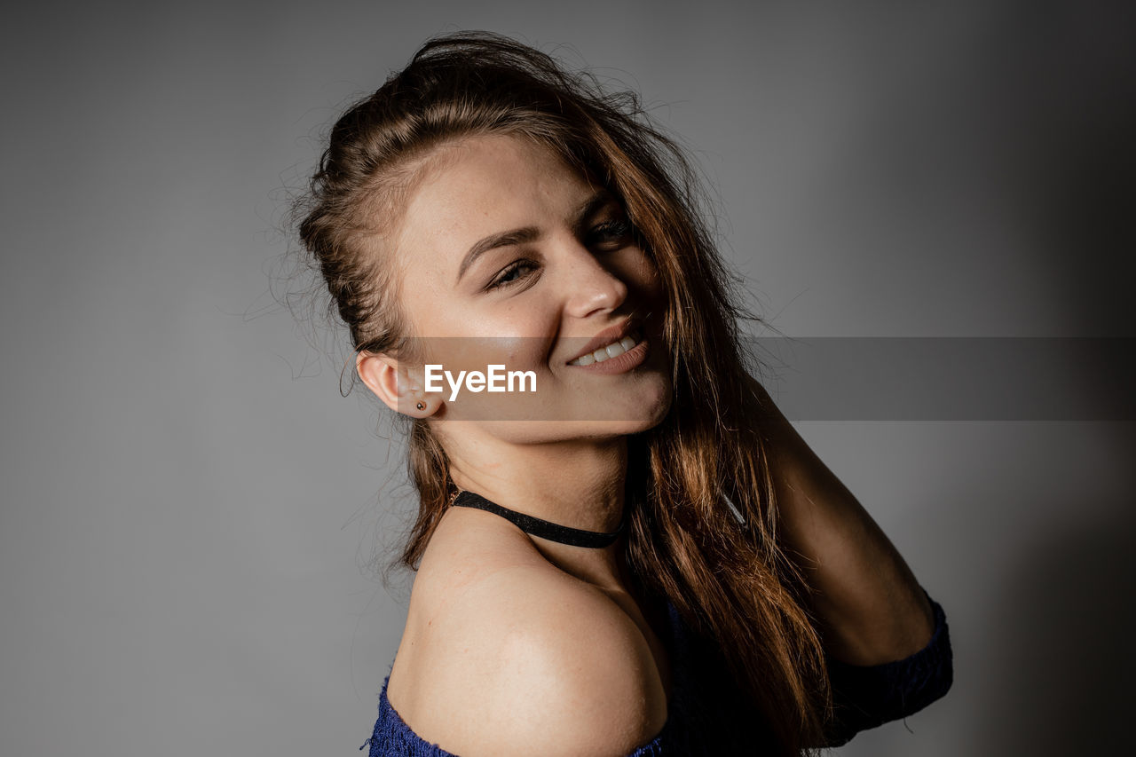 PORTRAIT OF A SMILING YOUNG WOMAN OVER WHITE BACKGROUND