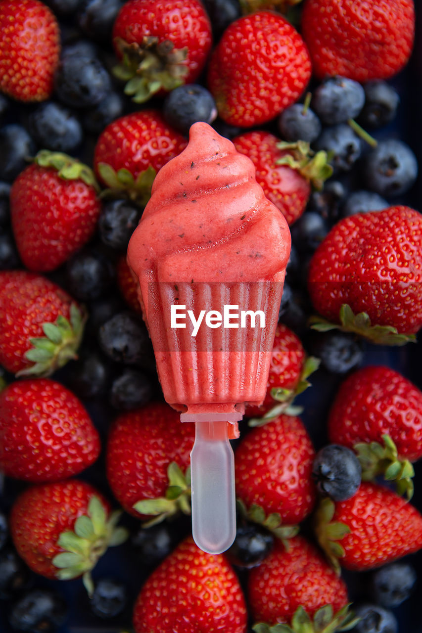 Fresh strawberry and blueberry ice cream close-up lies on fresh strawberry and blueberry.