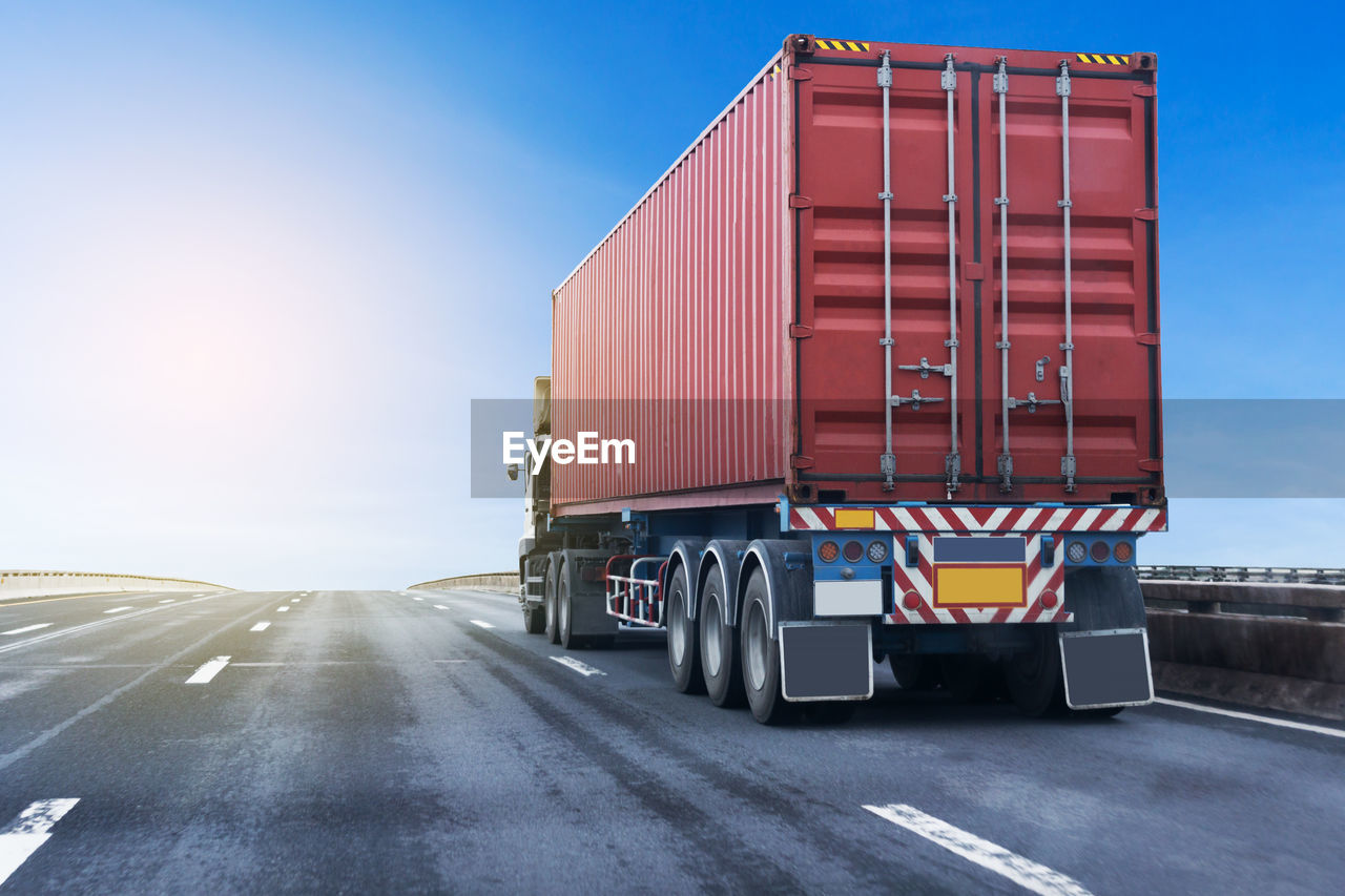 Truck moving on road against blue sky