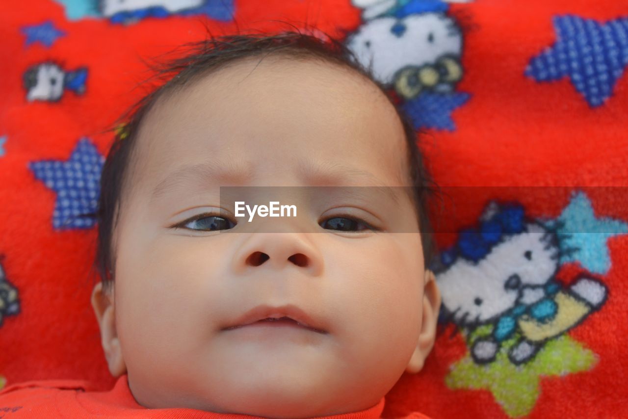 High angle portrait of cute baby boy lying on bed