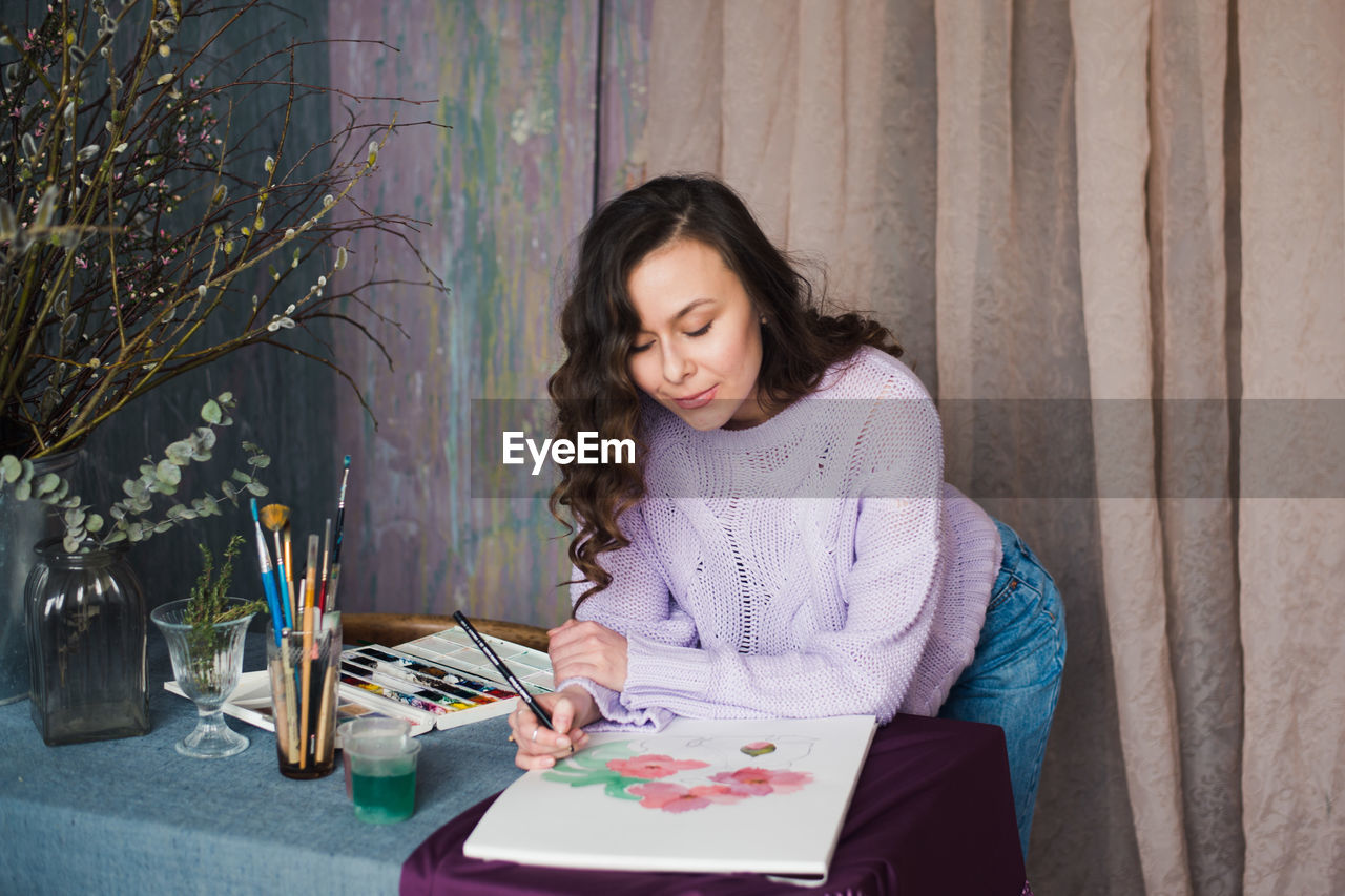 Smiling young woman painting at home