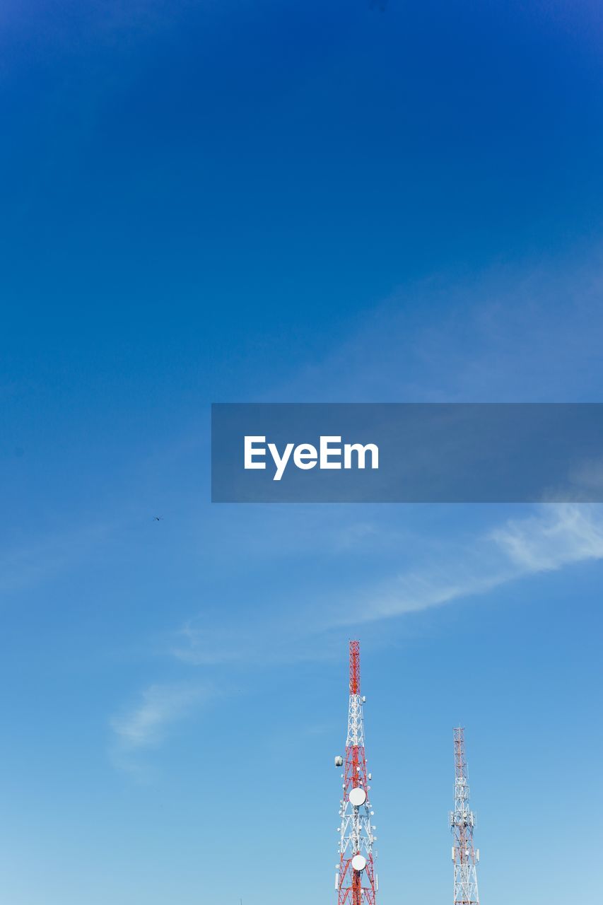 Low angle view of communications towers against blue sky