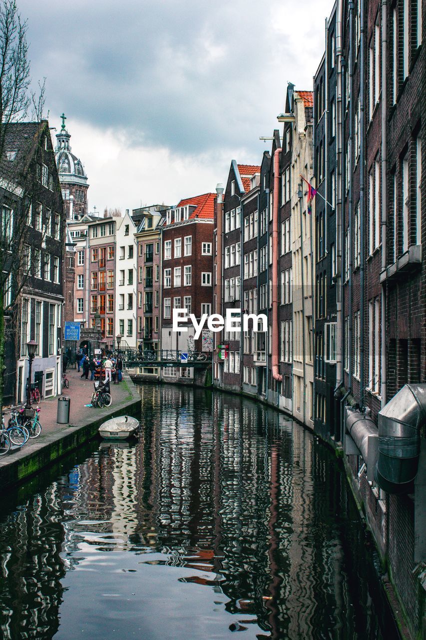 Canal amidst buildings in city against sky