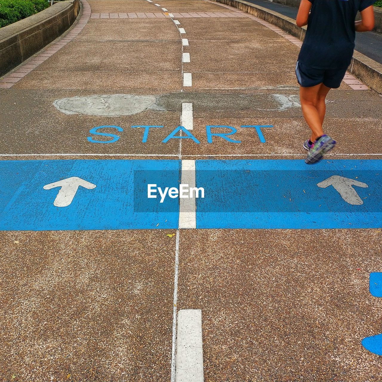 Low section of man running on road with start text 