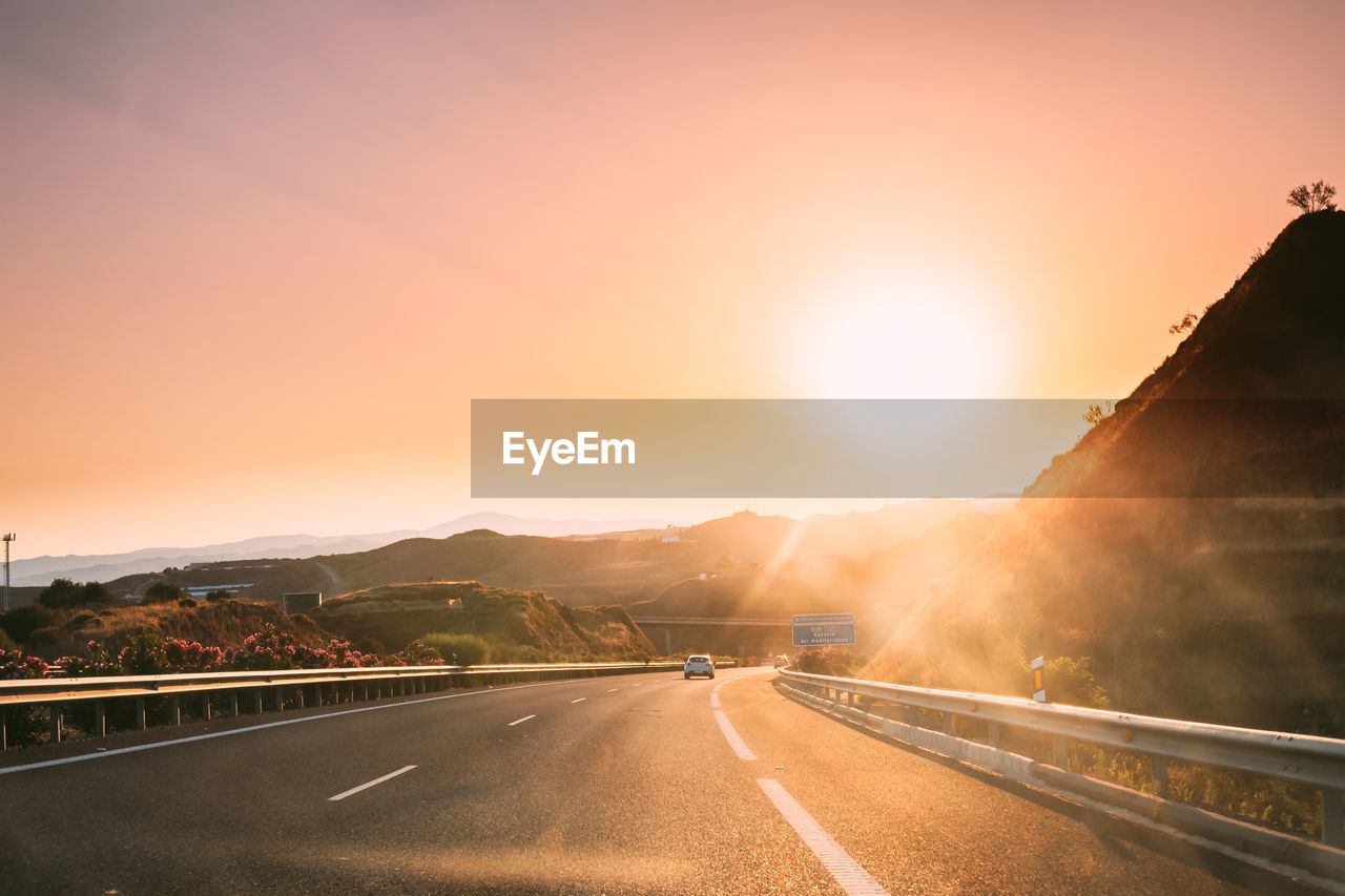 ROAD LEADING TOWARDS MOUNTAIN AGAINST SKY DURING SUNSET