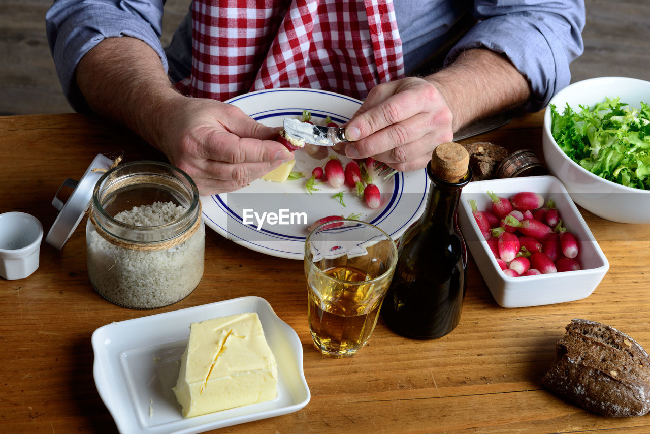 Midsection of man applying butter on radish