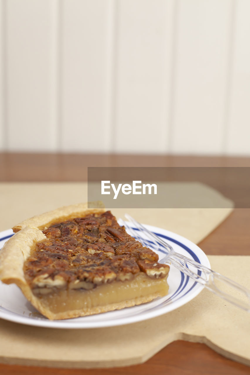 Two slices of pecan pie on a serving plate on a louisiana-shaped piece of plywood