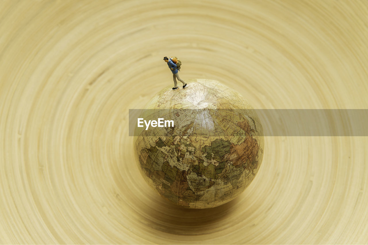 High angle view of figurine over globe on wooden table