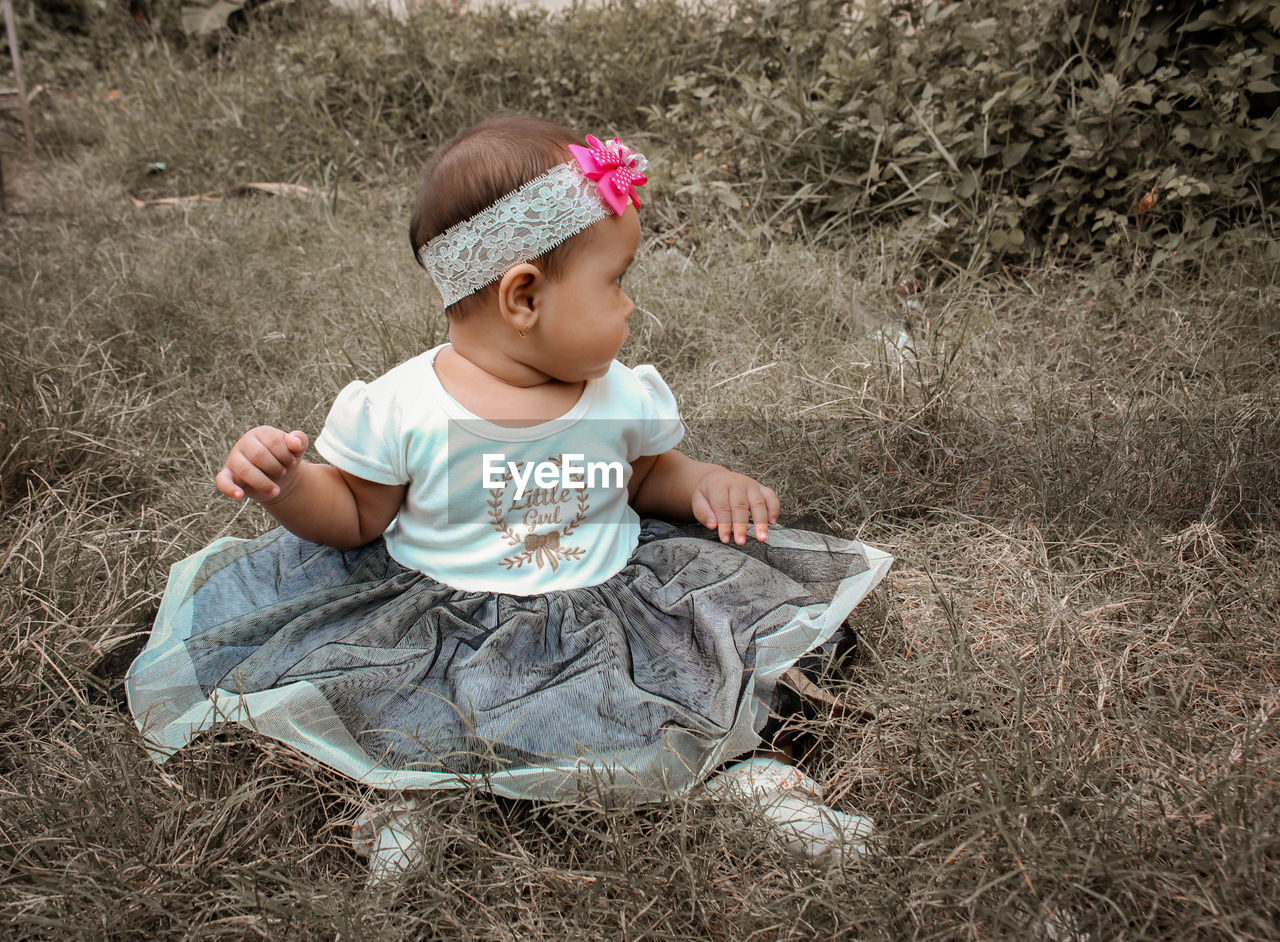 HIGH ANGLE VIEW OF BABY SITTING ON LAND