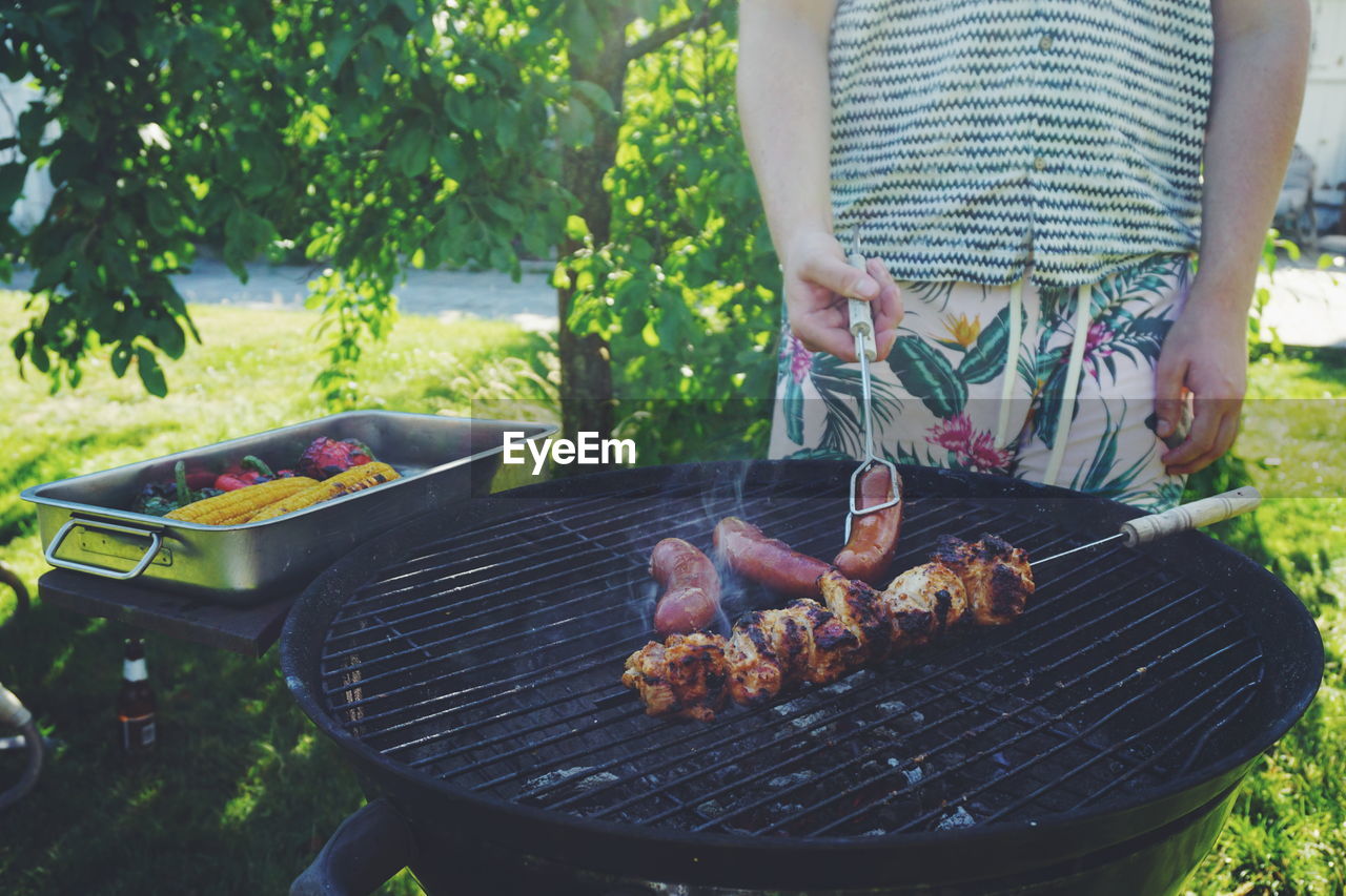 Man preparing food on barbecue grill in yard