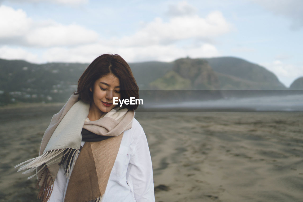 Smiling young woman wearing scarf at beach