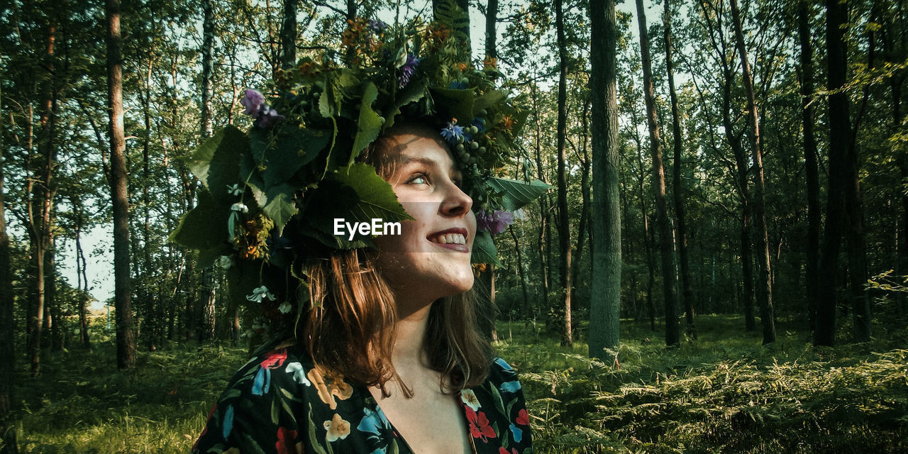 Smiling young woman wearing tiara standing in forest