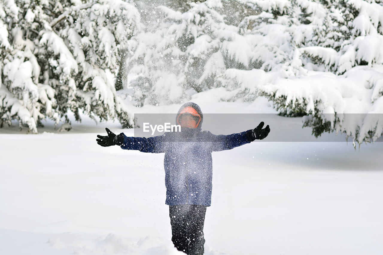 Young boy with arms outstretched in snow
