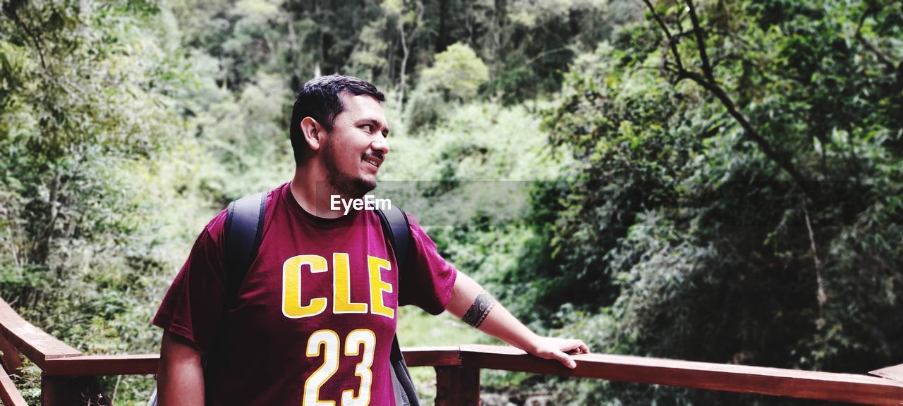 Portrait of young man standing against trees