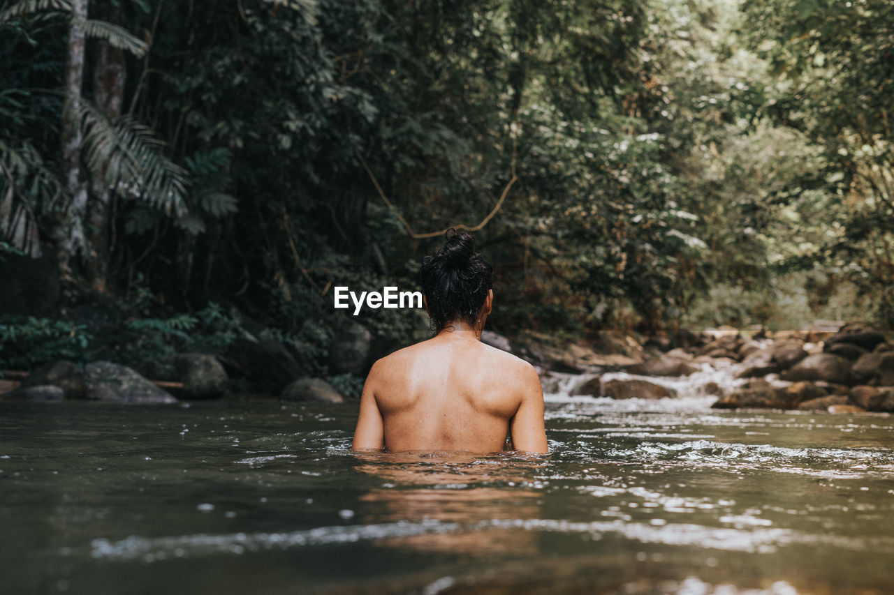 REAR VIEW OF SHIRTLESS MAN IN LAKE