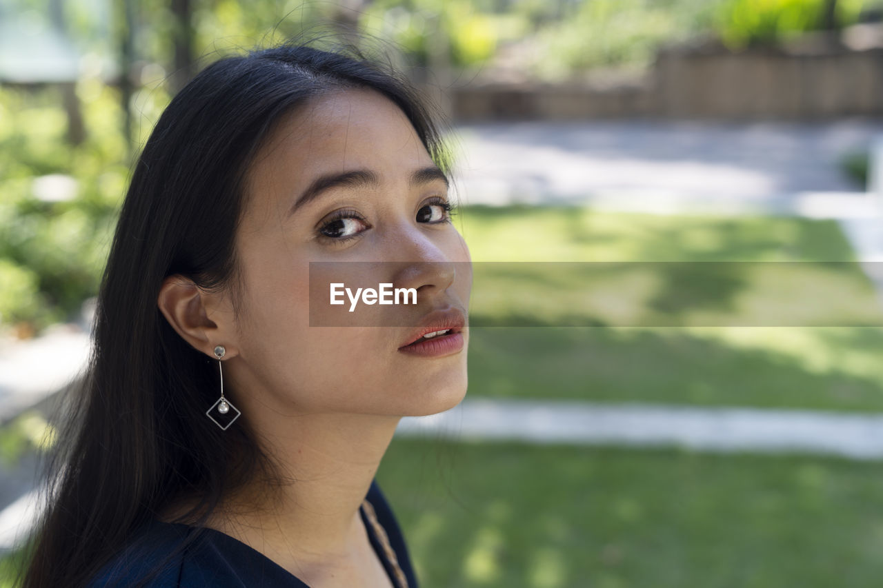 Close-up portrait of young woman looking away outdoors.